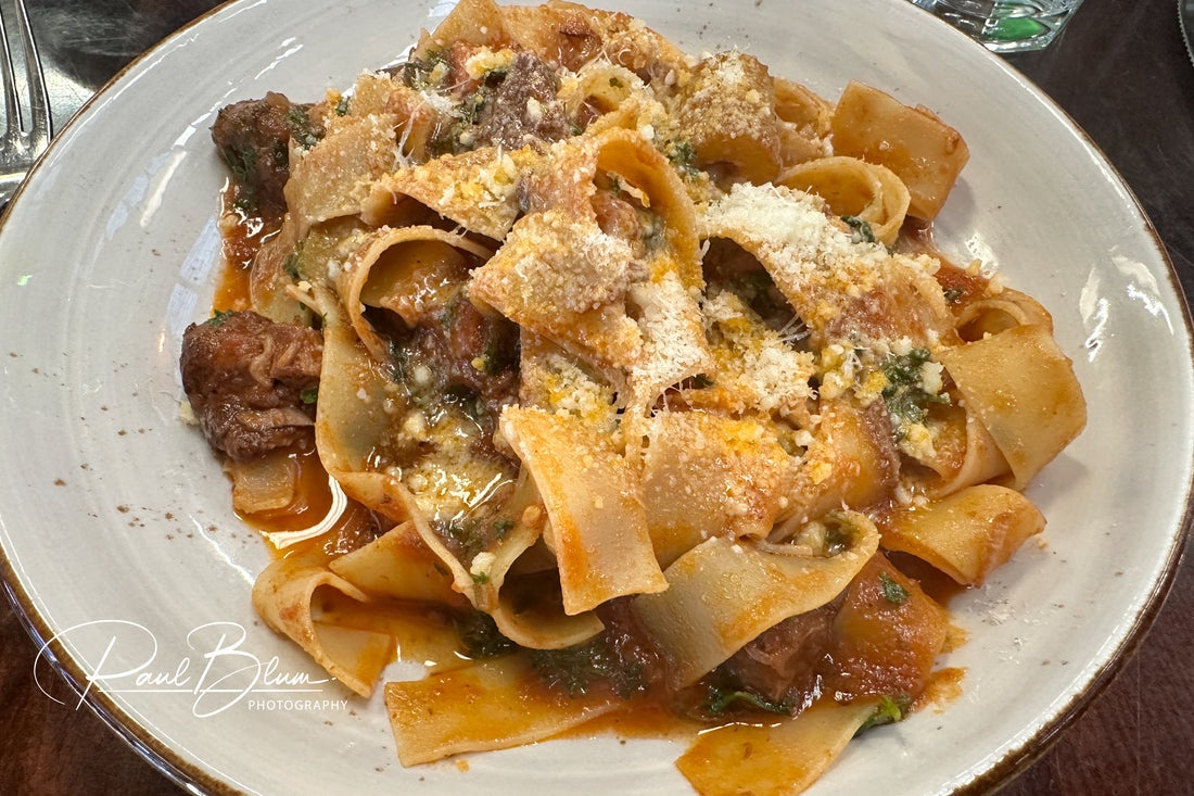 Wide ribbon-like pappardelle noodles topped with rich beef ragu and freshly grated Parmesan cheese, showcasing a perfect balance of texture and flavour